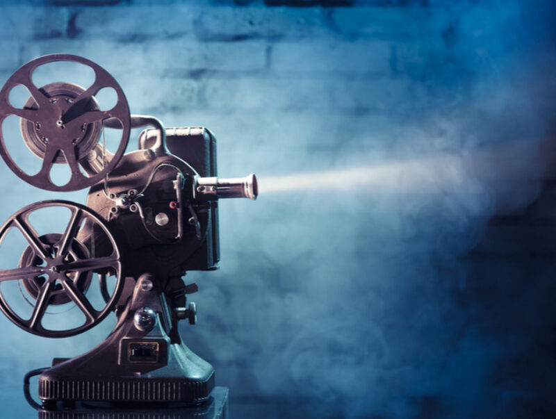 An old-fashioned film projector against a brick wall
