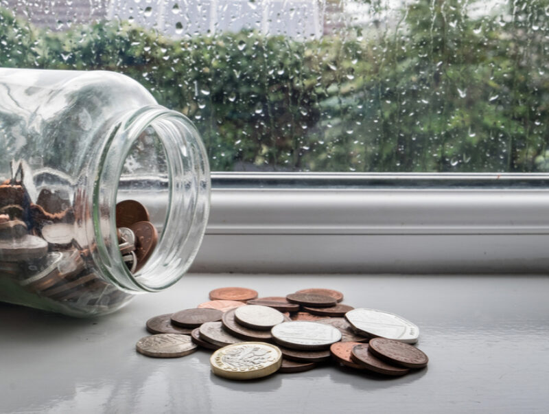 An emergency fund, spilt, on a windowsill with rain outside