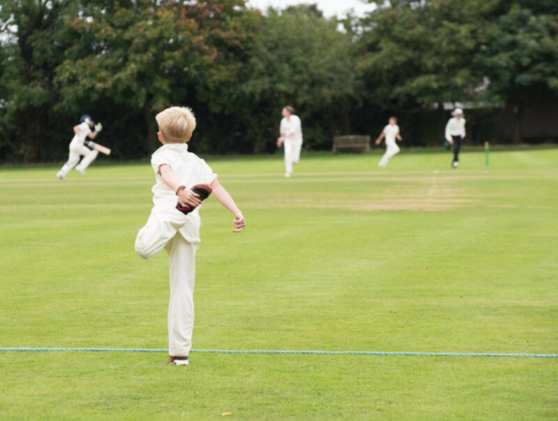 A young cricketer warming-up on the boundary as the game progresses