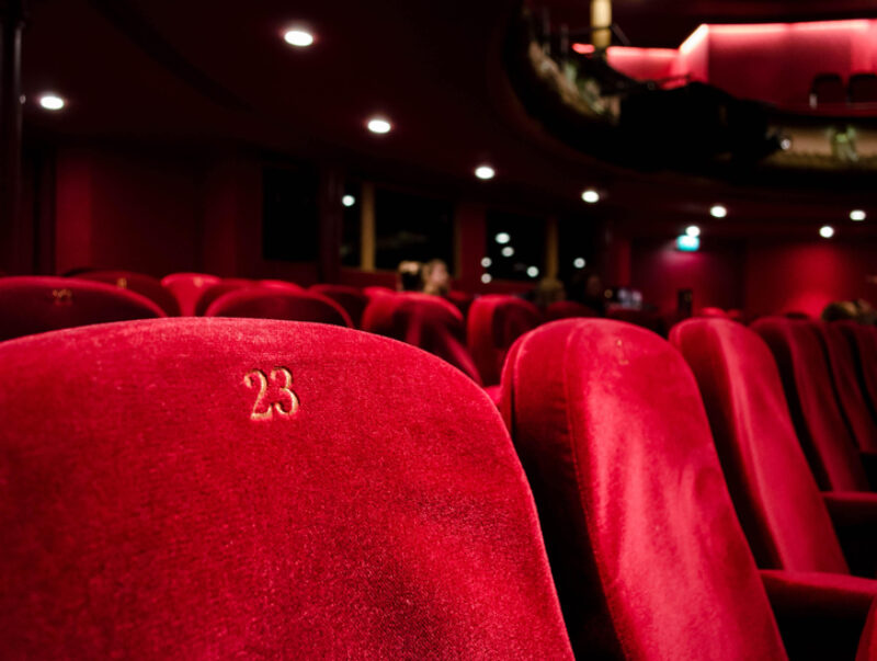 Close-up of a cinema seat in a largely empty theatre