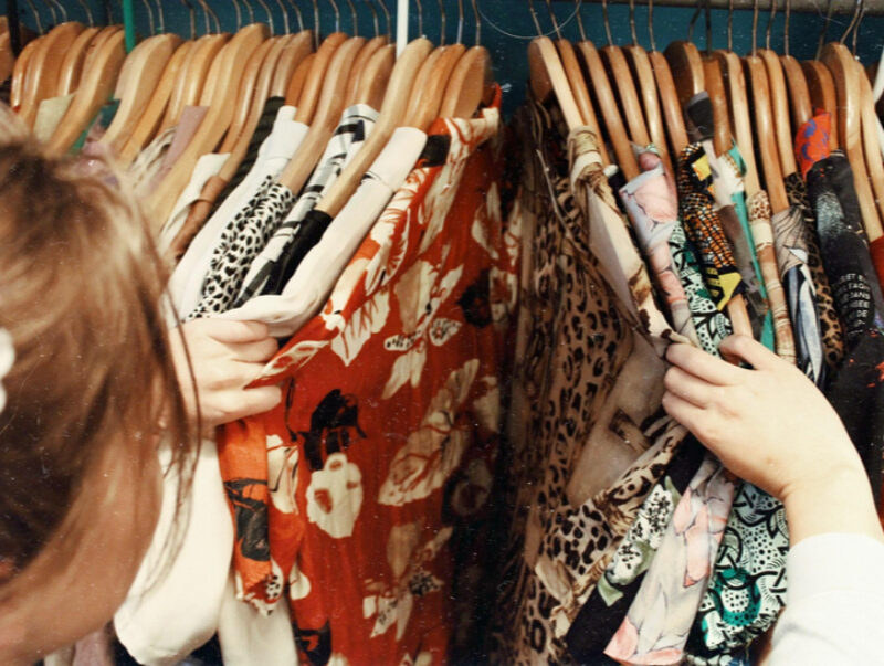 A young women rifling through dresses hanging on a rack