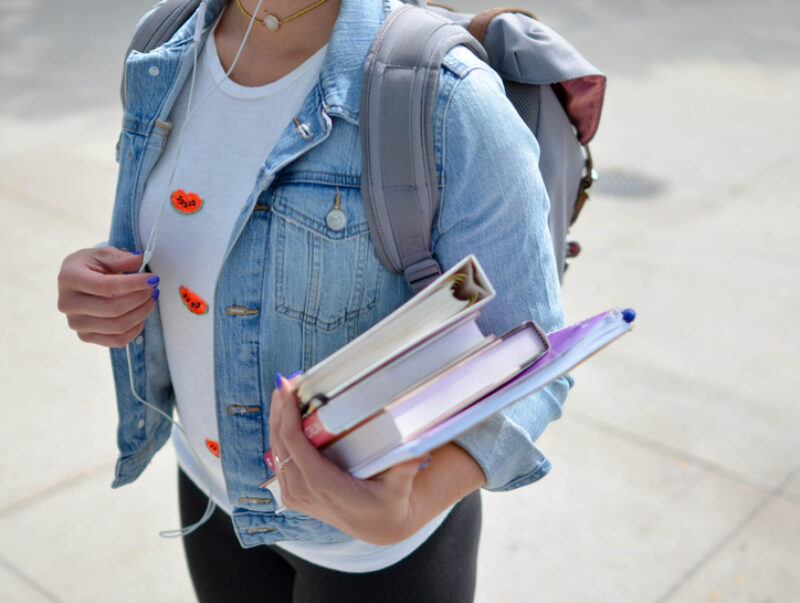 A student with a backpack, carrying books