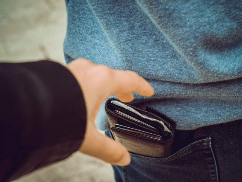 A pickpocket removing a wallet from a back trouser pocket