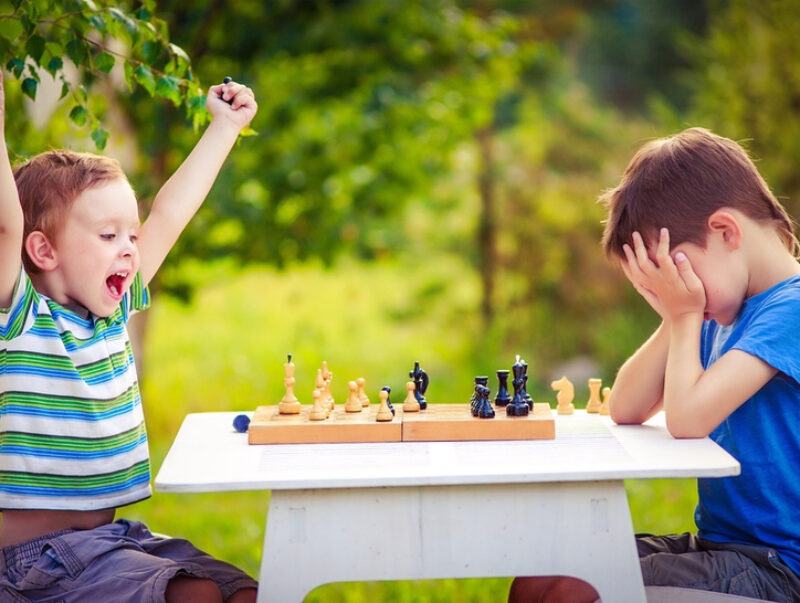 two boys playing chess, one has just won the game and is celebrating