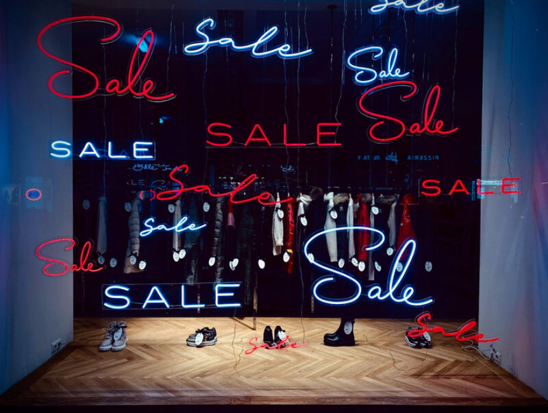 A shop window filled with neon “SALE” signs