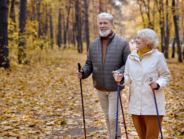 An older couple walk through the forest