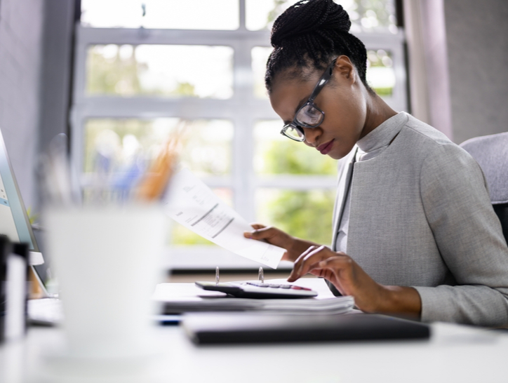 A woman looks at receipts with a calculator