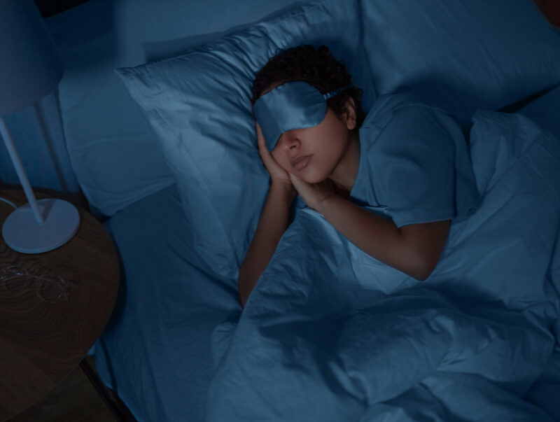 A young woman asleep with an eye mask on.