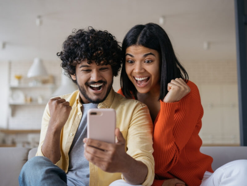 A couple celebrate while looking at a phone