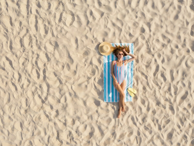 A woman sunbathing on an empty beach