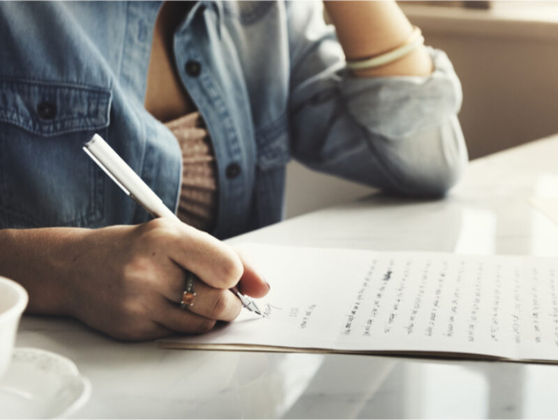 A woman writes a letter with pen and paper