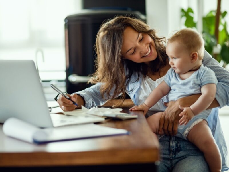 A woman holding a baby filling out paperwork